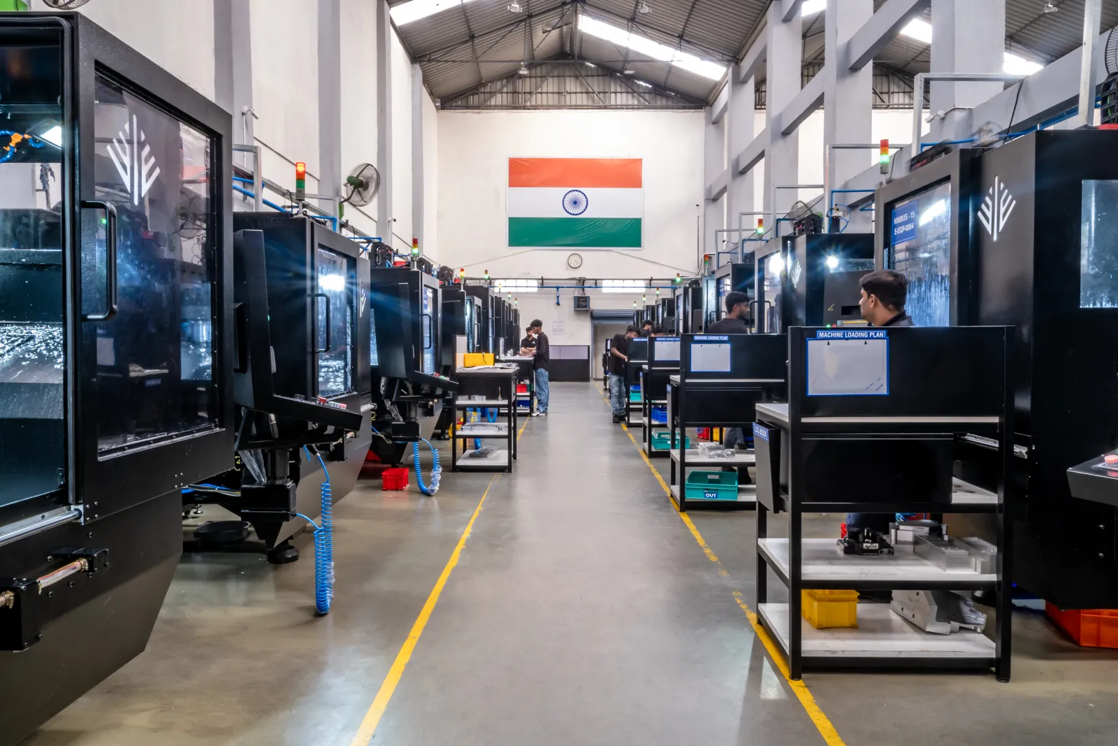 Ethereal Machines production floor — rows of five-axis CNC machines with operators at work, Bengaluru